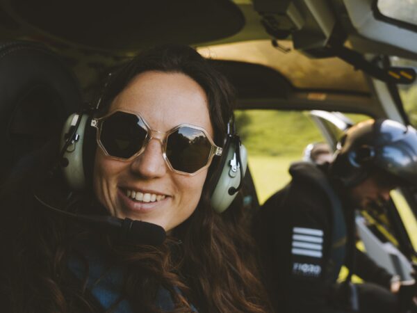 Smiling passenger wearing a headset in a Fjord Helikopter cabin.